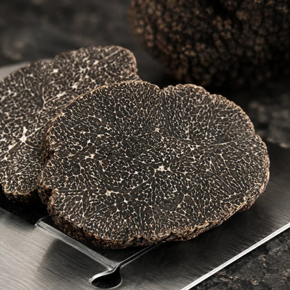 Cut Winter Black Truffle Tuber melanosporum showing dark marbled interior and premium texture
